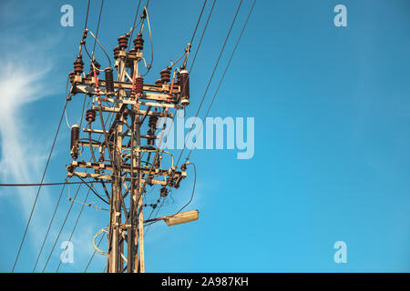 Utility pole supporting overhead power line cables against blue sky as copy space Stock Photo
