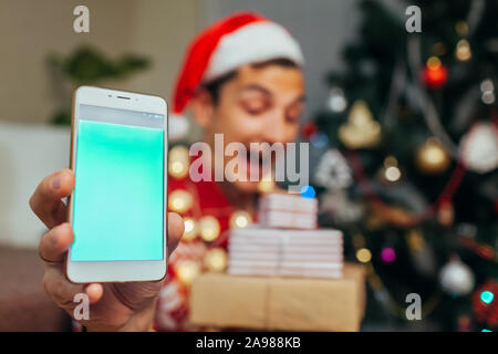 Christmas gifts delivery. Man ordered New year presents using smartphone. Happy guy holding gift boxes and phone Stock Photo