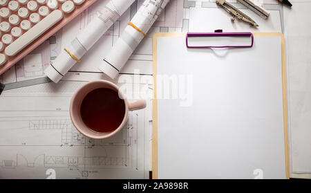 Female architect engineer office desk. Blueprint plans,  blank notepad and a pink computer keyboard, copy space, top view Stock Photo