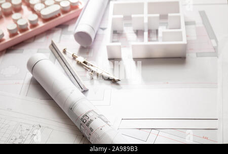 Female architect engineer office desk. Blueprint plans,  building project architectural design and a pink computer keyboard Stock Photo