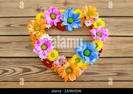 Heart made of flowers against wooden background Stock Photo