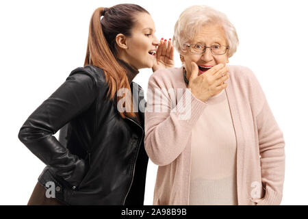 Young woman whispering to a surprised senior woman isolated on white background Stock Photo