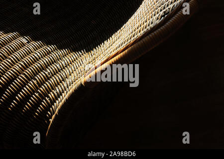 Detail of black and brown raided rattan chair with sunlight and shadow Stock Photo