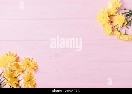 Flat lay frame of bouquets of yellow flowers on pink background, top view. Stock Photo