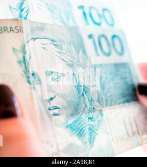 Brazilian currency. Photo of a woman holding money bills, one hundred reais and fifty reais notes; Stock Photo