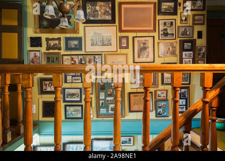 Vintage photographs and drawings on wall above maple wood staircase leading to ground floor inside an old 1835 Canadiana cottage style house Stock Photo