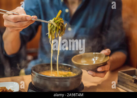 Male tourist eating Korean noodles in a Korean cafe. Travel Korea Concept Stock Photo