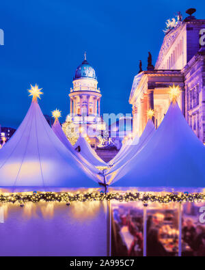 Romantic evening view of lit canvas tents of Chtristmas market in Gandarmenmarkt in Berlin, Germany, famous place for winter tourism around Xmas time. Stock Photo