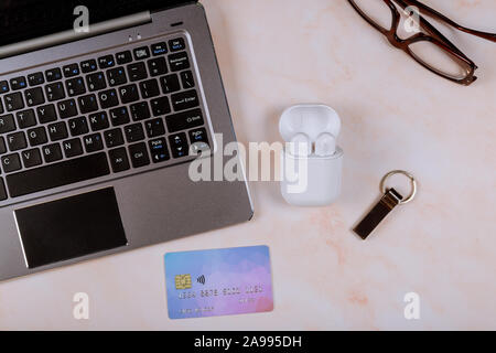 Online shopping on credit card with wireless headphones and computer keyboard on mouse glasses on bright wooden office desk. Stock Photo