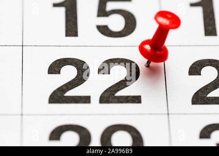 Pin on the date number 22. The Twenty second day of the month is marked with a red thumbtack. Pin on calendar. Stock Photo