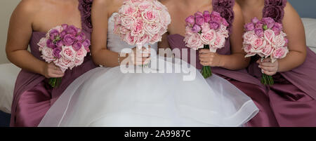A bride with her bridesmaids all holding their bouquets and posing prior to the wedding ceremony Stock Photo