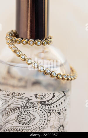 Tennis bracelet in gold and diamonds placed around a perfume bottle Stock Photo