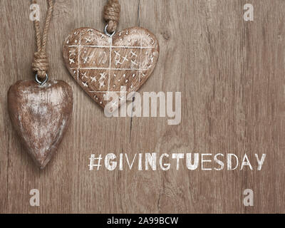 Giving Tuesday, global day of charitable giving. Give help, donations and support. Wooden hearts, flat lay on wood with text. Givingtuesday is a globa Stock Photo