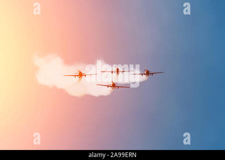 Four light-engine aircraft fly from far away leaving a smoky trail Stock Photo