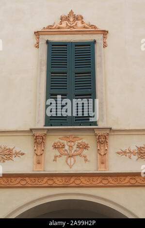 Como, Lombardy, Italy - 6th July 2019 : View of a framed window with closed shutter and beautiful baroque style decoration on a building in the city c Stock Photo