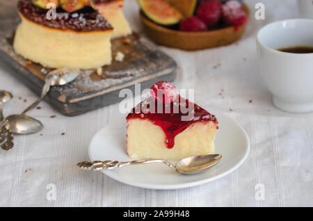 Slice of  New York style Cheesecake with raspberry topping on the kitchen Stock Photo