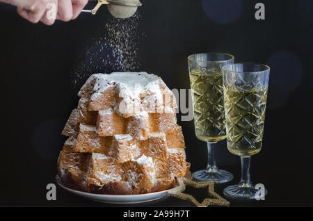 Italian Christmas cake Pandoro with glasses of sparkling wine on black background. Beautiful Xmas food concept. Copy space. Stock Photo