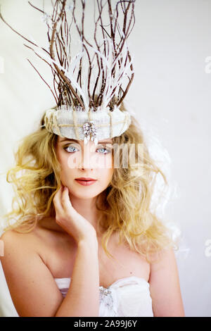 MACKAY, QUEENSLAND, AUSTRALIA - August 22, 2019: Beautiful young woman wearing an elaborate headpiece as she holds her hand to her face in contemplati Stock Photo