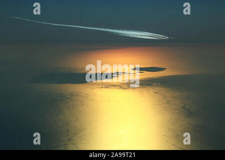 Engine exhaust contrails forming behind an Airbus A380 Super Jumbo while overflying the Maltese archipelago during a beautiful sunset Stock Photo