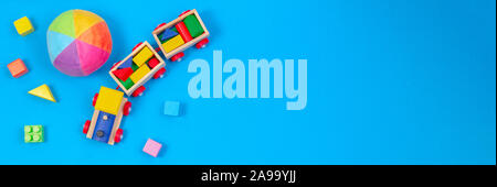 Baby kids toys banner background. Wooden train, soft ball and colorful blocks on blue background Stock Photo