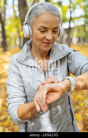 Mature pleasant woman checking her pulse outside Stock Photo
