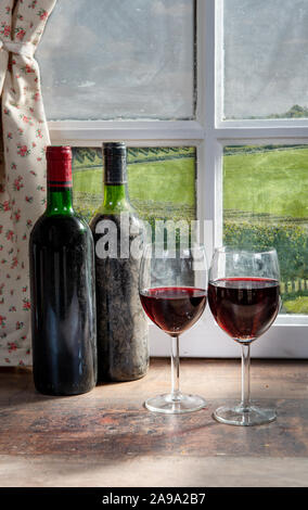 Composition with two wineglasses, grapes and bottles of red wine Stock Photo