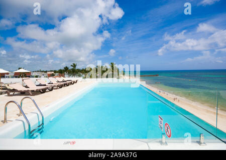 Empty infinity swimming pool on the roof of luxury hotel on the coast of sea. Summer holiday concept, Dominican Republic. Stock Photo