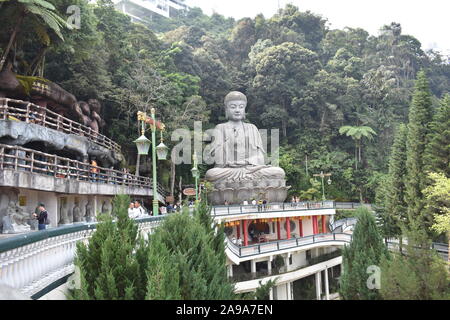 a giant stone statue of lord Buddha with tropical tress in the background in Genting highlands Malaysia Stock Photo