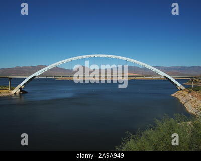 Roosevelt Lake Bridge taken from dam overlook - shows full coat-hanger shape and lovely colour on the water and in the sky Stock Photo