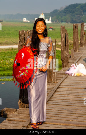 A Young Woman With A Parasol Standing On U Bein Bridge, Amarapura, Mandalay, Myanmar. Stock Photo
