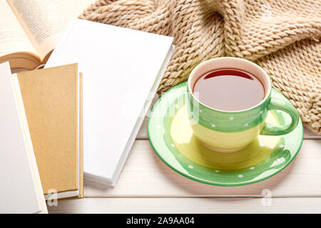 Still life on white wooden table top. Green cup of tea and stack of book in hard cover. Space for your text. Stock Photo