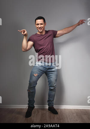 Fun humor grimacing young man showing crazy duck pose and making fun on grey background. Closeup. Full lenght Stock Photo