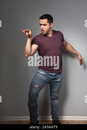 Fun humor grimacing young man showing crazy duck pose and making fun on grey background. Closeup Stock Photo