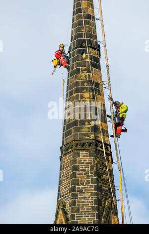Steeplejack on church spire in Southport, Merseyside. UK Weather: 14th Nov, 2019.  Cold, cloudy conditions with a stiff breeze for steeplejacks carrying out urgent repairs to Holy Trinity Church Steeple in the town centre. Sunny conditions with a light breeze are expected to continue to allow maintenance, storm damage repair and restoration work to continue. Holy Trinity Church, on Manchester Road, was placed in category B of the At Risk register, meaning there is an “immediate risk of further rapid deterioration, loss of structural integrity with the condition of the church branded “poor”. Stock Photo