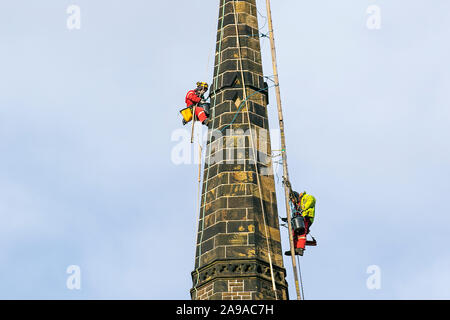Steeplejacks on church spire in Southport, Merseyside. UK Weather: 14th Nov, 2019.  Cold, cloudy conditions with a stiff breeze for steeplejacks carrying out urgent repairs to Holy Trinity Church Steeple in the town centre. Sunny conditions with a light breeze are expected to continue to allow maintenance, storm damage repair and restoration work to continue. Holy Trinity Church, on Manchester Road, was placed in category B of the At Risk register, meaning there is an “immediate risk of further rapid deterioration, loss of structural integrity with the condition of the church branded “poor”. Stock Photo