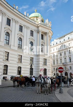 Carriages and horses outside St. Michael's Gate of Hofburg Palace overlooking Michaelerplatz in Vienna Stock Photo