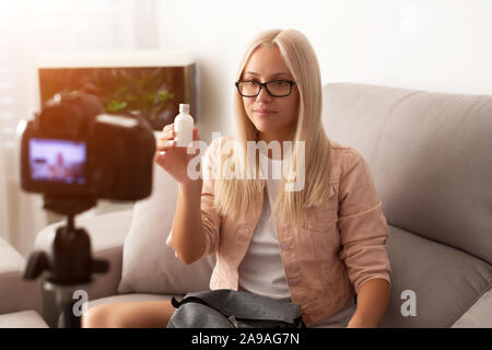 Famous blogger. Cheerful female vlogger is showing cosmetics products while recording video and giving advices for her beauty blog Stock Photo