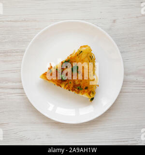 A piece of spaghetti omelette on a white plate on a white wooden surface, top view. Flat lay, overhead, from above.