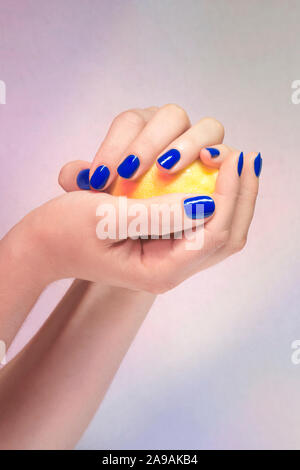 Mains manucurées de bleu tenant/ jouant avec un citron jaune / Manicured hands of blue holding / playing with a yellow lemon Stock Photo