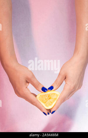 Mains manucurées de bleu tenant/ jouant avec un citron jaune / Manicured hands of blue holding / playing with a yellow lemon Stock Photo