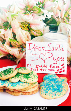 Homemade Christmas snowman shaped sugar cookies with blue green and red sprinkles and a hand written affectionate note to Santa Claus. Stock Photo