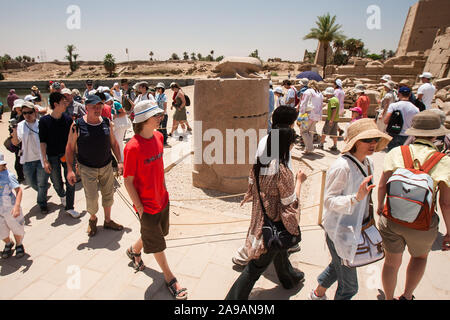 Karnak, Luxor, Egypt - April 28, 2008: Tourists circle around a granite statue of a scarab for luck in Karnak temple near Luxor, Egypt. Stock Photo