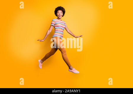 Full body profile photo of jumping high dark skin wavy lady walking down street positive good mood wear casual summer clothes isolated bright yellow Stock Photo
