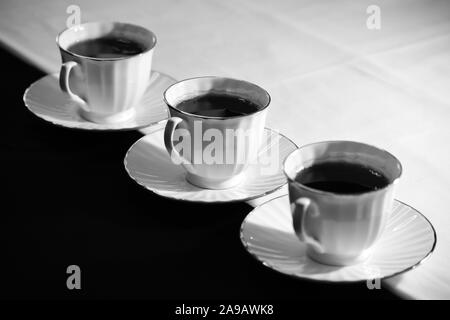 Three cups and saucers with black tea. Stock Photo