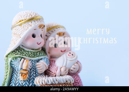 the holy family, the child jesus, the virgin mary and saint joseph, and the text merry christmas, on a pale blue background Stock Photo