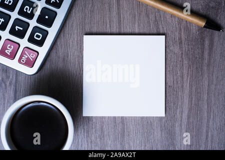 high angle view of a blank note, a cup of coffee, a pen and an electronic calculator on a gray wooden table Stock Photo