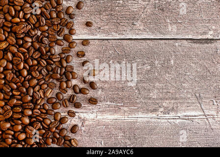 Roasted coffee beans on dark brown rustic weathered wood panel background with lots of copy space. Top View. Stock Photo