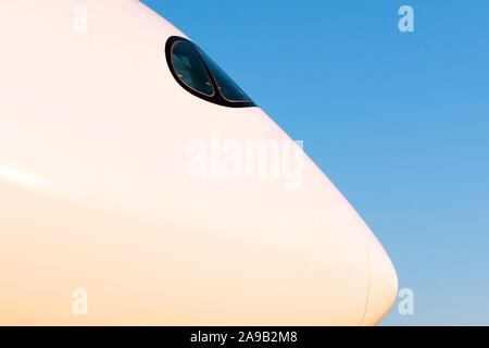 Modern passenger airplane nose side profile cockpit in evening light sunset blue sky Stock Photo