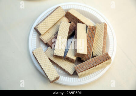 Various confectionery on plate, wafer witch chocolate layers and cookies on white background . waffles in a white plastic plate. Stock Photo
