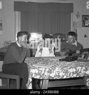 Three boys with harmonica and gutar playing their favourite songs, Germany 1956 Stock Photo